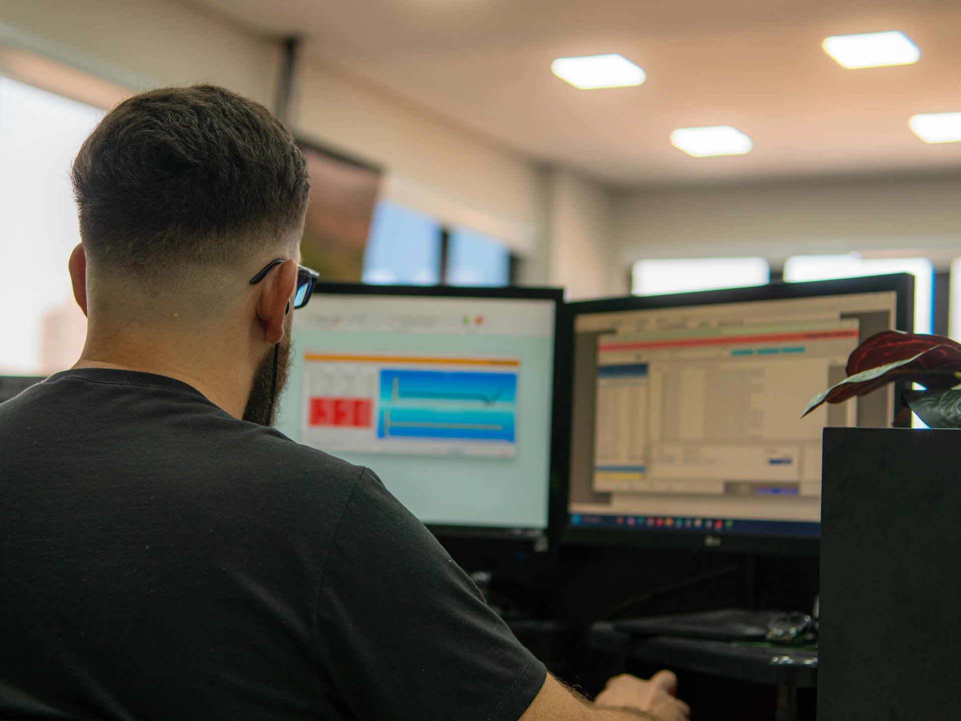 Profissional da PCE analisa indicadores financeiros em dois monitores