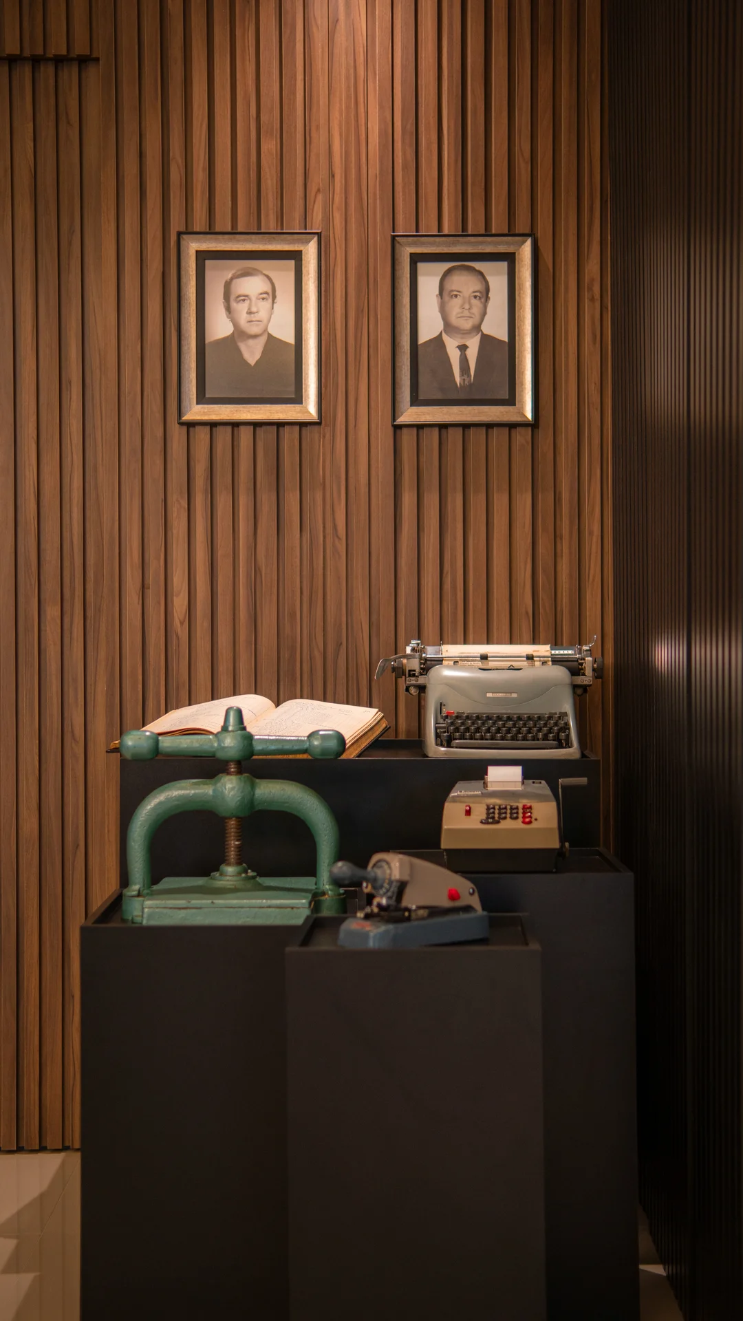 Memória da história da PCE com retratos dos fundadores e equipamentos contábeis